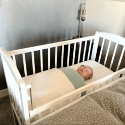houten co-sleeper met baby naast bed voor verhuur